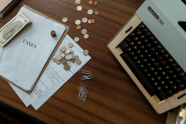 Overhead view of a vintage desk with typewriter, coins, and tax documents.
