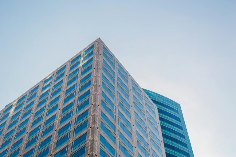 Low angle view of a modern skyscraper with reflective glass windows against a clear sky.