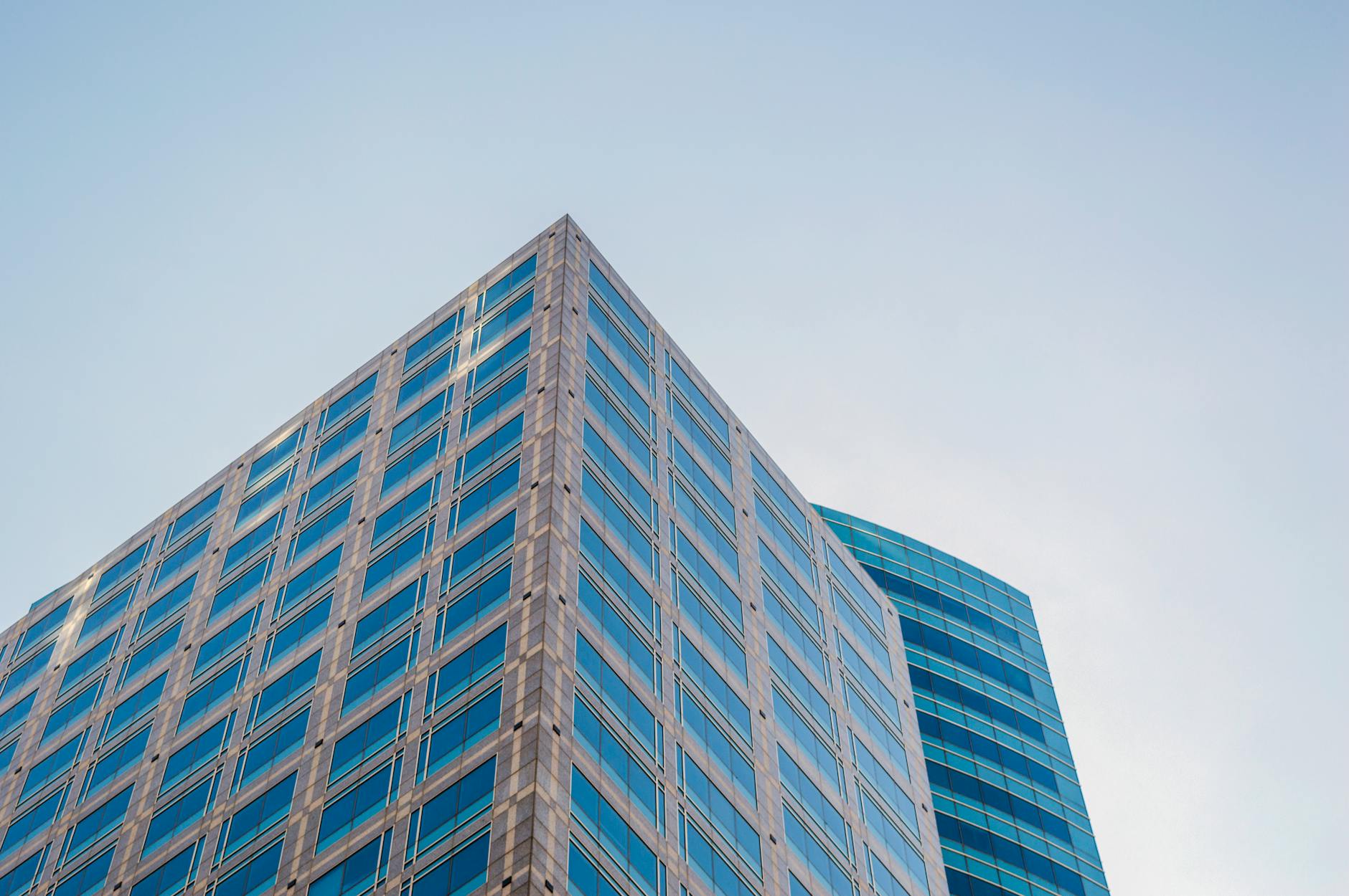 Low angle view of a modern skyscraper with reflective glass windows against a clear sky.
