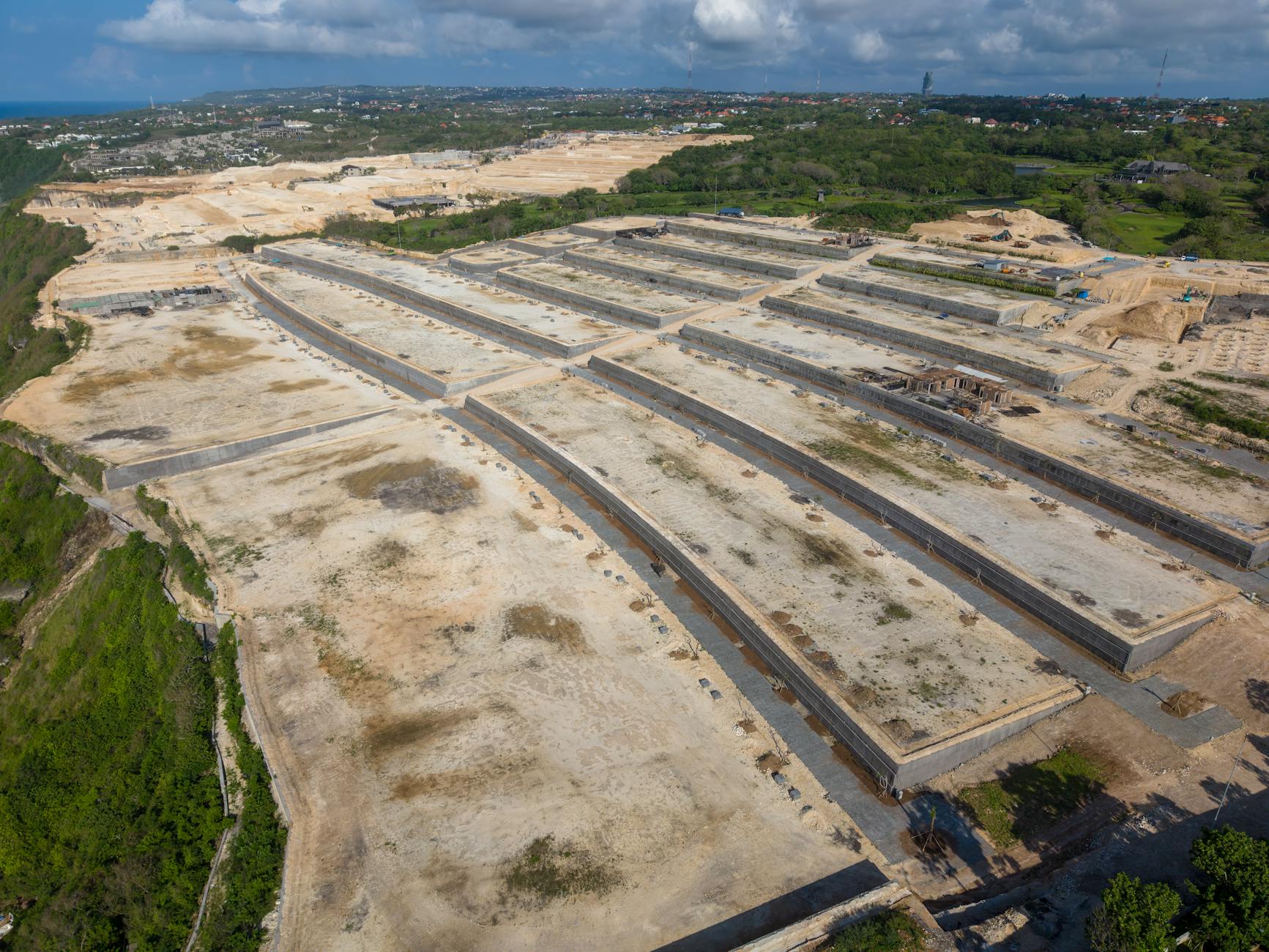 Expansive aerial view of a large construction site in Bali, Indonesia under a cloudy sky.