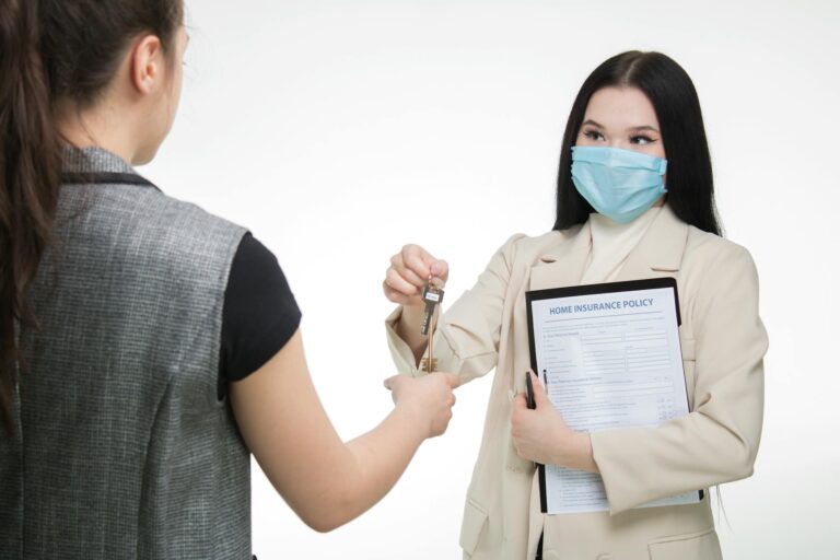 Real estate agent in a face mask hands keys to a client, illustrating safe business practices.