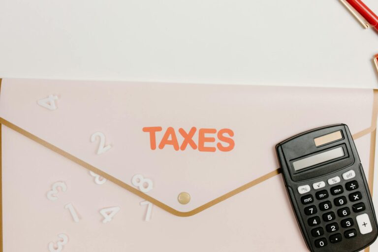 Flat lay of a calculator and folder labeled 'Taxes' for finance and accounting.