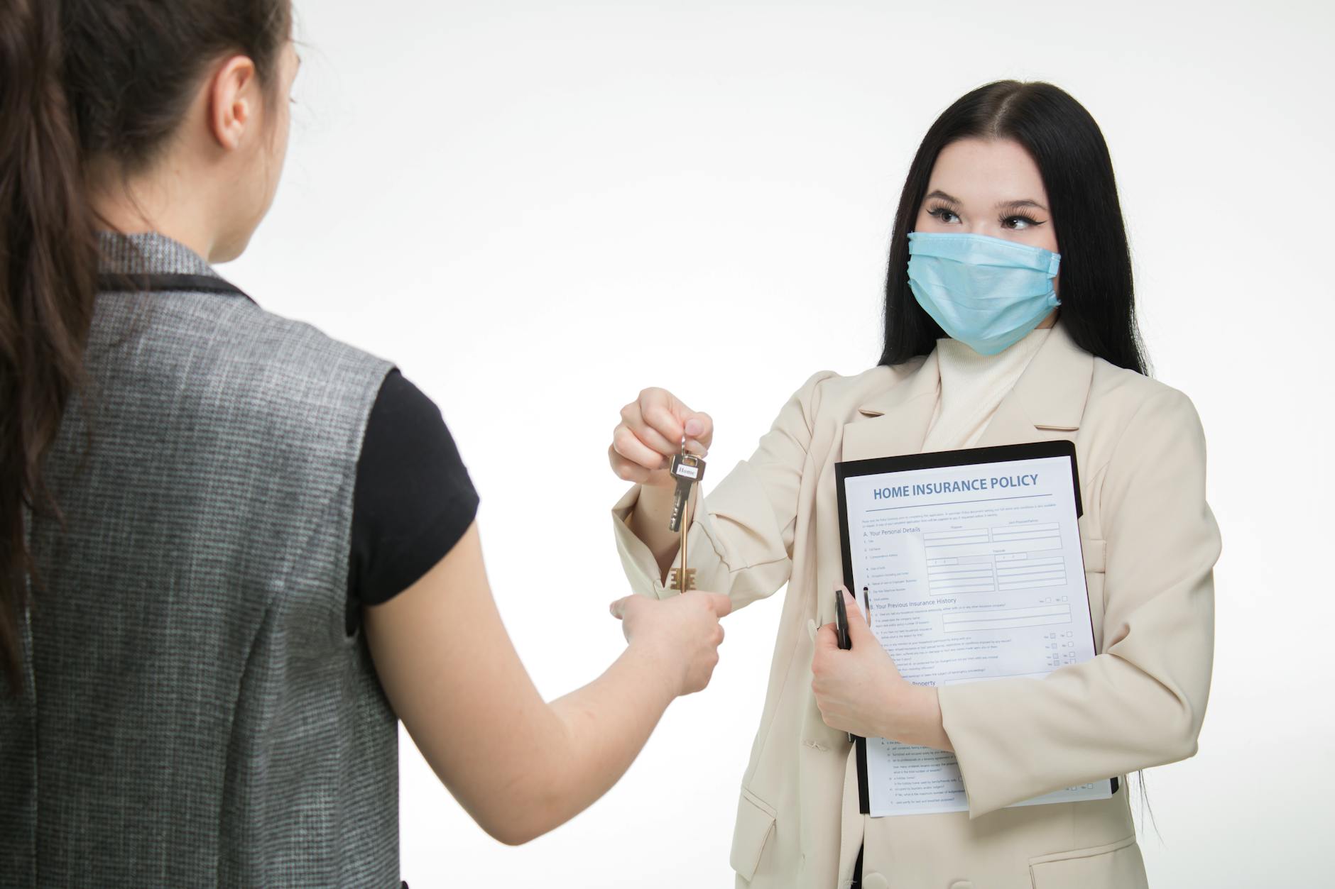 Real estate agent in a face mask hands keys to a client, illustrating safe business practices.