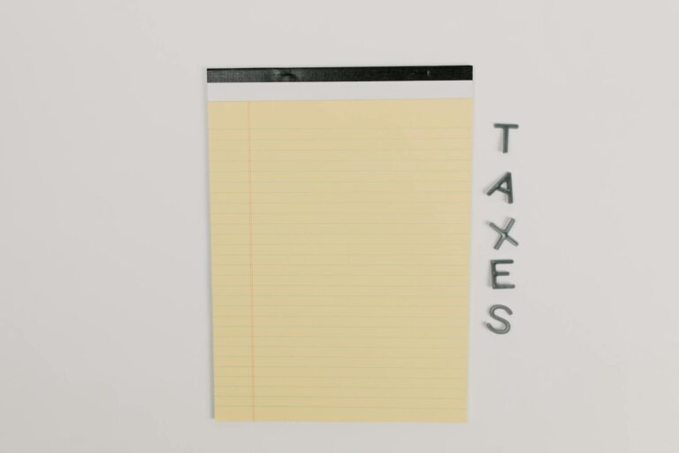 Close-up of a yellow legal pad and the word 'TAXES' on a white surface, ideal for finance themes.