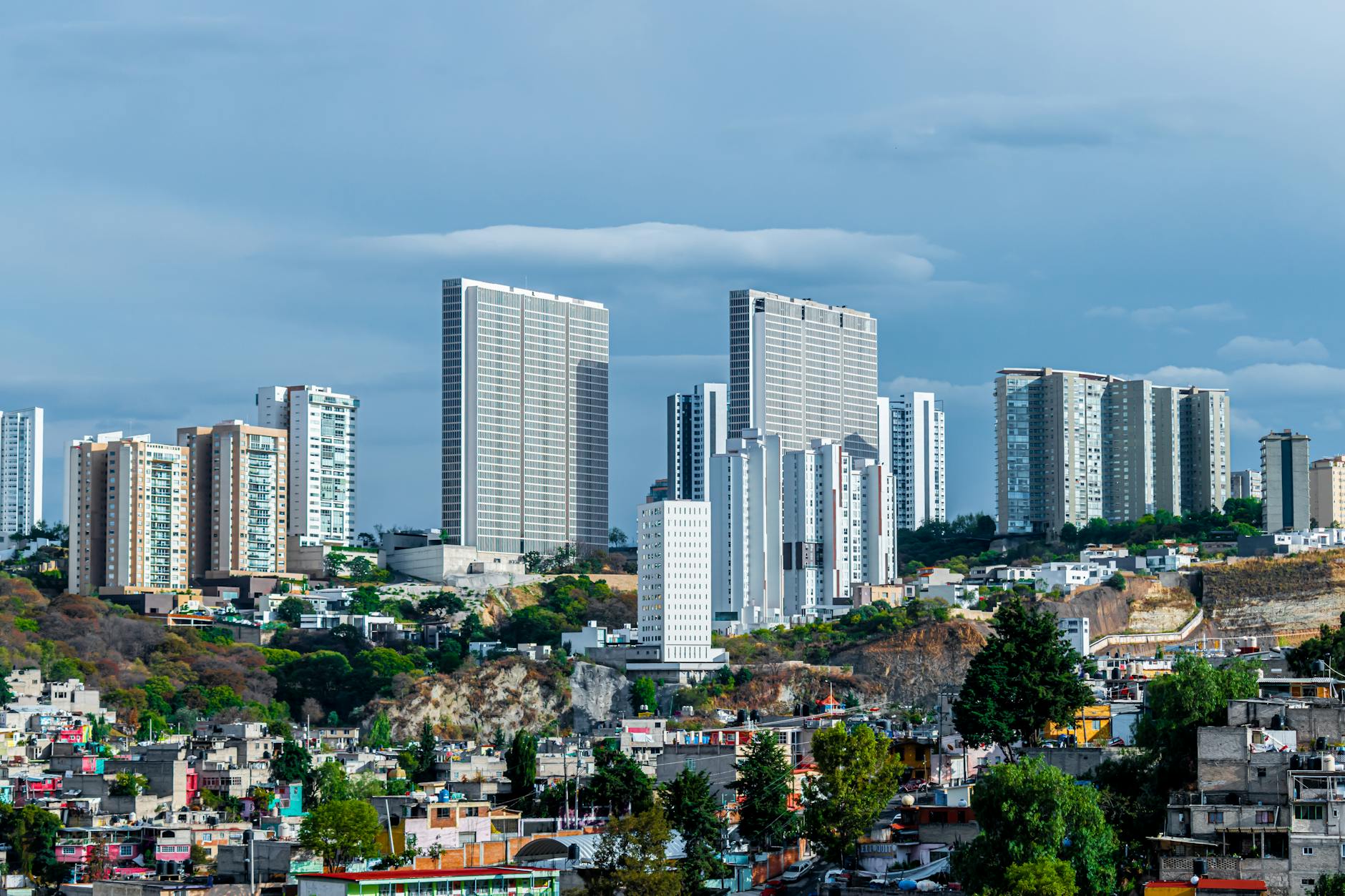 Panoramic view of a modern cityscape featuring high-rise buildings under a blue sky.