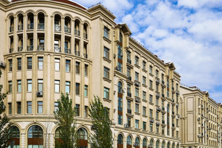 A classic urban residential building with rounded corners and detailed facades under a clear blue sky.