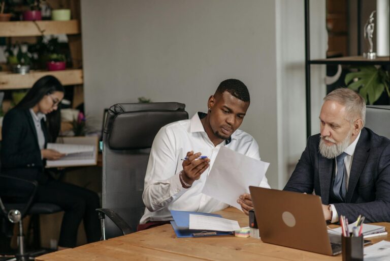 Business professionals discussing documents in a modern office environment with focus on teamwork and collaboration.